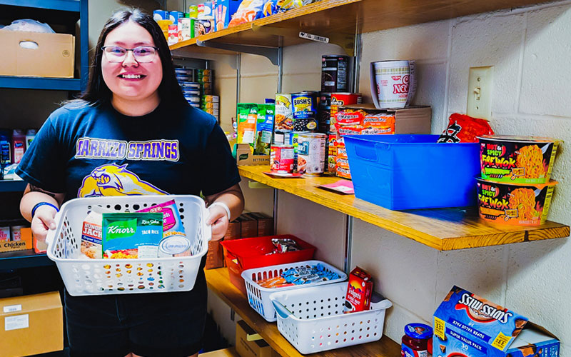 Student holds a basket full of foods available at the Student Food Pantry.