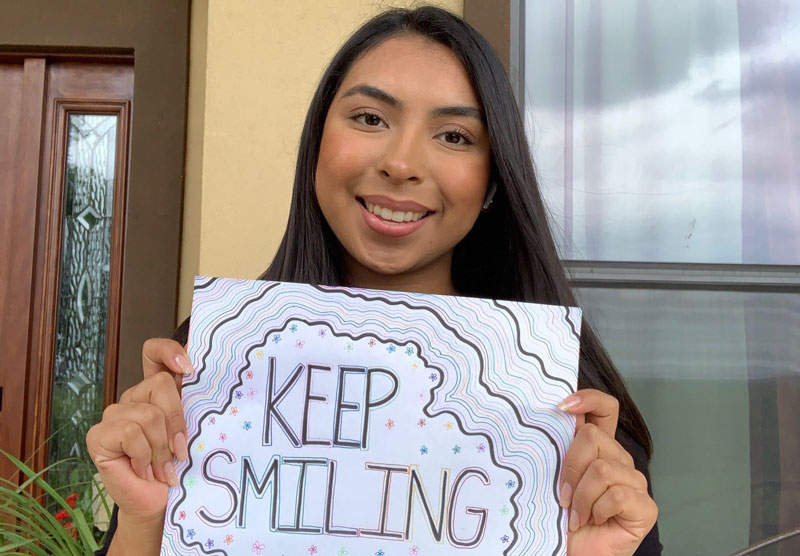 female student holding a keep smiling sign