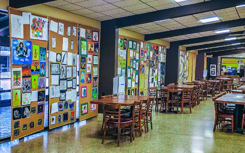 Artwork for the 2023 Creative Arts Ceremony is mounted on cork boards lining the Matthews Student Center Cafeteria windows.